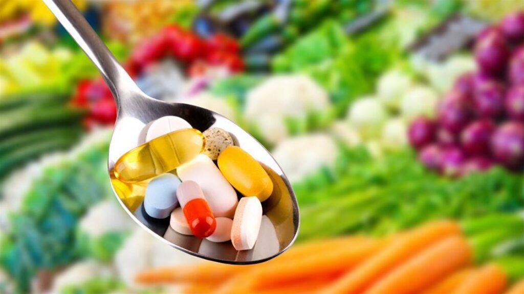 Vitamins: A spoon filled with different vitamin supplements.