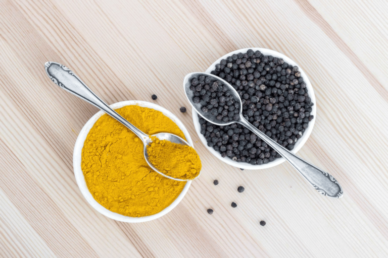 Two bowls filled with turmeric and black pepper