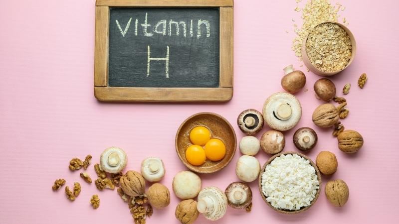 Pink background with biotin rich foods like eggs, mushrooms, oats.